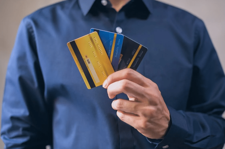 Compare card Machine Costs-a man holding 3 credit cards -ComparedBusiness